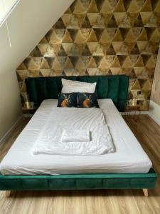 Cama en habitación con sofá verde en Székely Fogadó, en Tunyogmatolcs