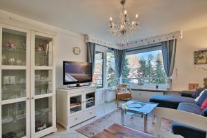 a living room with a television and a chandelier at Carpe Diem Carpe Diem Appartement 109 in Niendorf