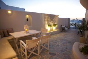 um pátio com uma mesa, cadeiras e um sofá em Sunset View Villa Santorini - with Outdoor Jacuzzi em Firostefani