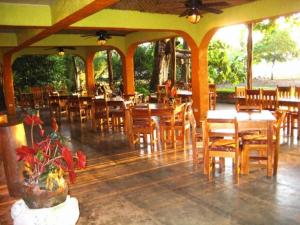 um restaurante com mesas e cadeiras de madeira em Iguana Lodge Beach Resort em Puerto Jiménez