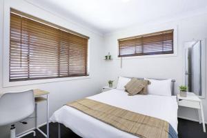 a bedroom with a bed and a desk and two windows at Bright Private Room in Pleasant Ashmore in Gold Coast