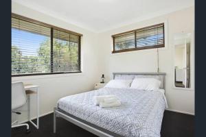 a bedroom with a bed and a desk and two windows at Bright Private Room in Pleasant Ashmore in Gold Coast