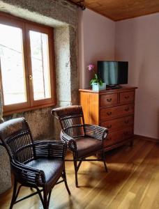 a living room with two chairs and a dresser with a tv at Casa Rosalia in Lobios