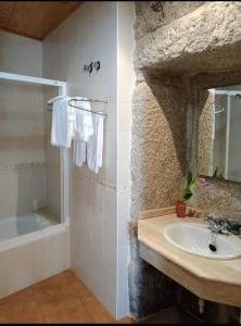 a bathroom with a sink and a stone wall at Casa Rosalia in Lobios