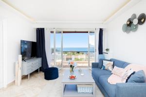 Suite Riviera - Sea View - Clim - 50M Plage - Residence de standing - Spacieux 180 M2 - Parking في كان: غرفة معيشة مع أريكة زرقاء ونافذة كبيرة