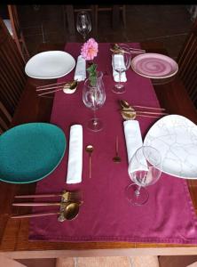 a table with purple table cloth and plates and glasses at Casa Rosalia in Lobios