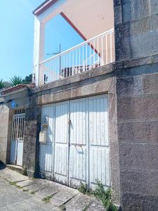 un par de puertas blancas de garaje en un edificio en Casco antiguo con patio y a 5 min de la playa, en Baiona