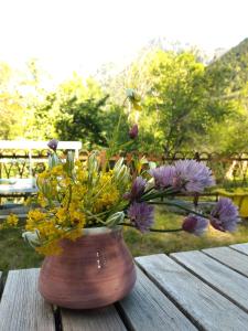 un jarrón lleno de flores en una mesa de madera en Chambre ou gîte dans une maison de montagne - De Suzon à Zélie, en Entraigues