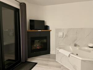 baño con chimenea, bañera y TV en Private Room On Waterfront Property With Hot Tub Firepit - Sea Esta en Ucluelet