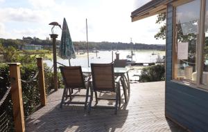 een veranda met een tafel en stoelen en uitzicht op het water bij Kipper Cottage in Wootton Bridge