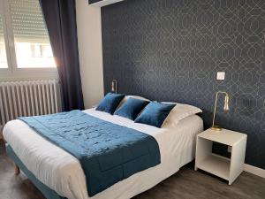 a bedroom with a large bed with a blue blanket at Hotel Alpes Cevennes in Guilherand