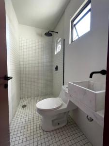 a white bathroom with a toilet and a sink at Casa Ixaya by Barrio México in Guadalajara