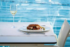a plate of food on a table with a glass of wine at Dukley Hotel & Resort in Budva