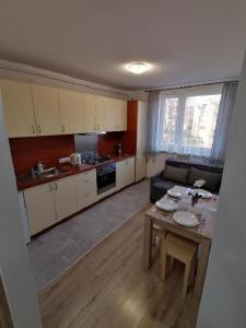 a kitchen and living room with a table and a couch at Mieszkanie Reymonta in Krynica Zdrój