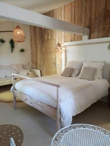 a bedroom with a large white bed and wooden walls at Le Sens des Merveilles in Mane