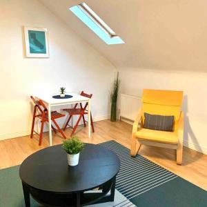 a living room with a table and a yellow chair at Flat 7 EIA House in Belfast