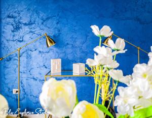 een blauwe muur met een lamp en witte bloemen bij Blu Euphoria Studio in Mamaia Nord – Năvodari