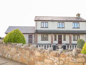 una casa bianca con un muro di pietra di Derriens Farmhouse a Enniskillen