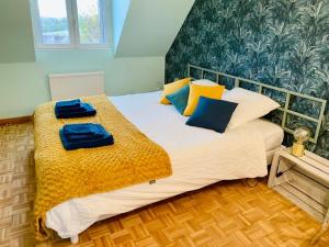 a bedroom with a large bed with blue and yellow pillows at La LocaLuna in Civray-de-Touraine