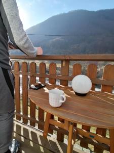 eine Person, die auf einem Balkon mit einem Tisch und einer Kaffeetasse steht in der Unterkunft počitniška hiška MEDVEJKE in Slap ob Idrijci