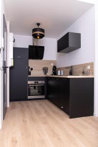 una cucina con armadi neri e pavimenti in legno di Appartement 70m2 hyper centre avec baignoire balnéo a La Flèche Altre 3 foto