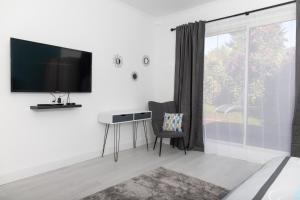 1 dormitorio con escritorio y TV en la pared en Appartement 70m2 hyper centre avec baignoire balnéo, en La Flèche