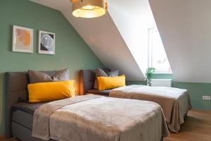 two beds with yellow pillows and a couch in a room at Bauhaus Apartment - Netflix & Wifi in Chemnitz
