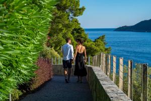 un hombre y una mujer caminando por un camino junto al agua en Dukley Hotel & Resort, en Budva