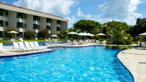 una piscina con sedie e ombrelloni di fronte a un hotel di Carneiros Beach Resort a Praia dos Carneiros
