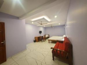 sala de estar con mesa y sofá rojo en MG TOWER Hotel, en Trivandrum