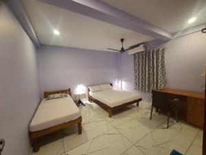 Habitación con 2 camas, mesa y escritorio. en MG TOWER Hotel, en Trivandrum