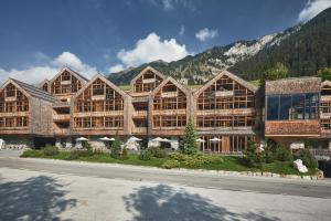 a large wooden building with mountains in the background at Tenne Lodges in Racines