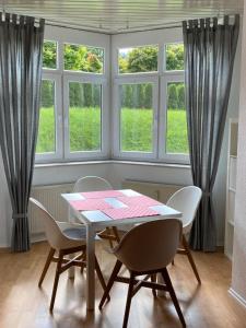ein Esszimmer mit einem Tisch, Stühlen und Fenstern in der Unterkunft Ferienwohnung Bad Laasphe Altstadt in Bad Laasphe