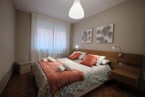 um quarto com uma cama grande e almofadas laranja em APARTAMENTO CON TERRAZA em Ponteceso