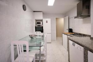 uma cozinha com uma mesa de vidro e electrodomésticos brancos em APARTAMENTO CON TERRAZA em Ponteceso