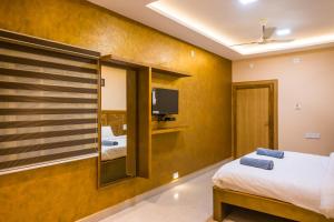 a bedroom with a bed and a tv on a wall at HOTEL SOUTHERN HERITAGE in Udupi