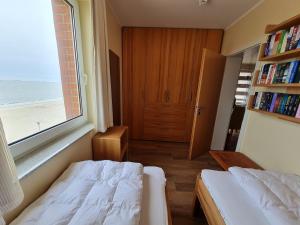 a bedroom with two beds and a window and a book shelf at Seeblick in Wyk auf Föhr