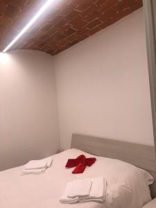 Una cama con toallas blancas y un arco rojo. en Elegante e spazioso bilocale in zona Certosa (FI), en Florencia