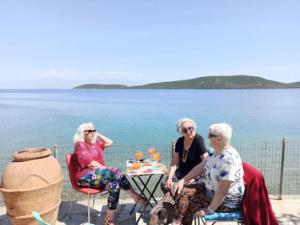 three women sitting at a table by the water at Little Bit Of Heaven in Soúrpi