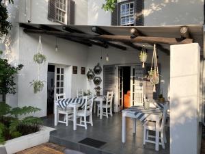 een patio met witte stoelen en een tafel en een tafel en stoel bij Battiss Guest House in Pretoria
