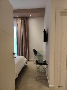 1 dormitorio con 1 cama, 1 silla y 1 mesa de cristal en Capricci di Vento - Design Guest House, en La Maddalena