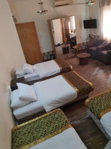 Habitación con 3 camas y sala de estar. en Crystal Hotel فندق كريستال, en Nablus