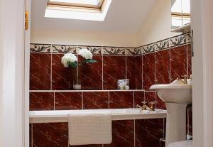 a bathroom with red tiled walls and a sink at Linden Apartment in Stirling