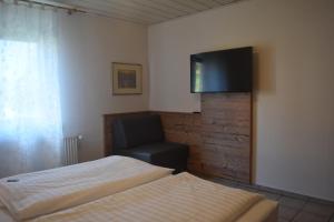 een slaapkamer met een bed en een stoel en een flatscreen-tv bij Ferienhaus Storchenblick in Bann