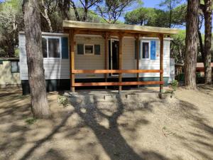 una pequeña casa en el bosque con un árbol en Mipro Mobilhome 5 en Lido di Spina