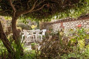 a patio with white chairs and a table in a garden at Bluebell Cottage - Norfolk Cottage Agency in Burnham Market