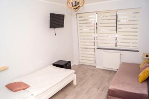 um pequeno quarto branco com uma cama e uma janela em Zibi i Pod Topolami em Łazy