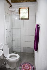 a small bathroom with a toilet and a window at Mini Chalés Madeira Beach in Ubatuba