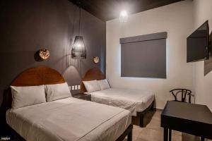 een kamer met 2 bedden, een bureau en een televisie bij HM HOTEL EXPRESS in Colima