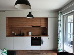 a kitchen with white cabinets and a black oven at Green Apartment Międzywodzie in Międzywodzie
